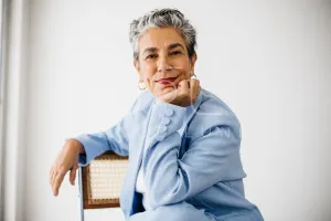 Elegant female professional sitting on a chair, dressed in a sharp office suit and grey hair